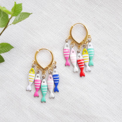 Fish charm hoop earrings on a white cloth.