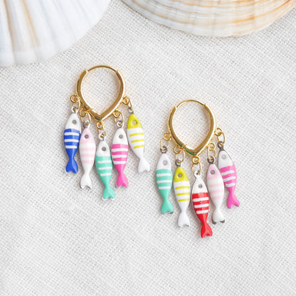 Fish charm hoop earrings on a white cloth.