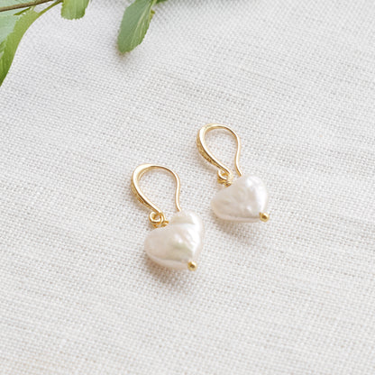 Freshwater pearl heart earrings on a white cloth.