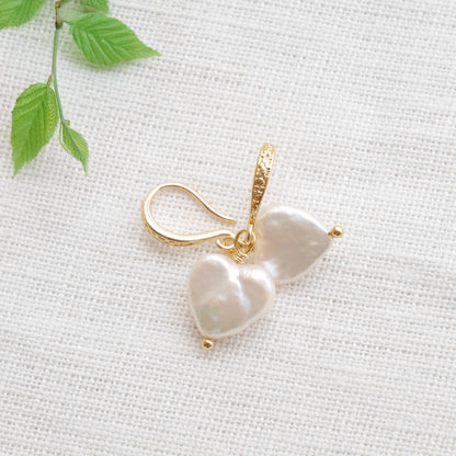 Freshwater pearl heart earrings on a white cloth.