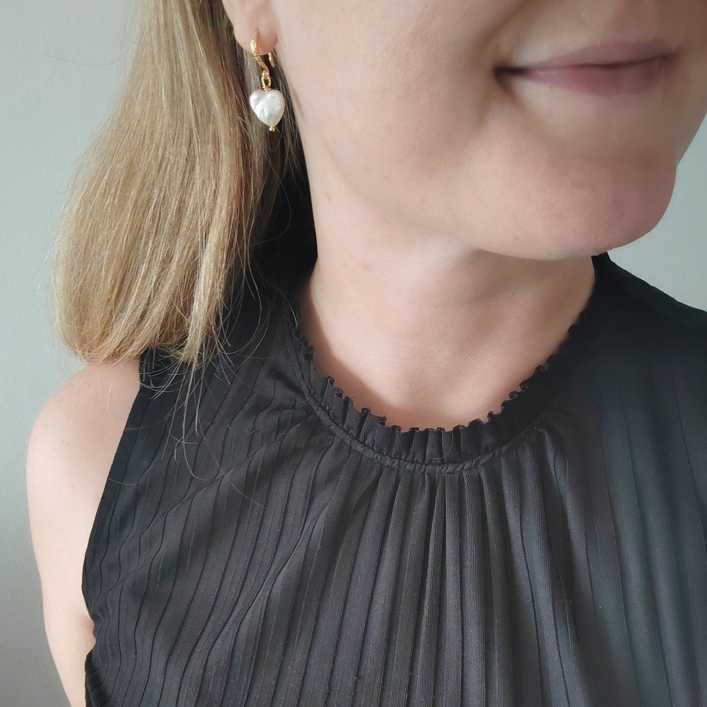 Woman wearing freshwater pearl heart earrings.