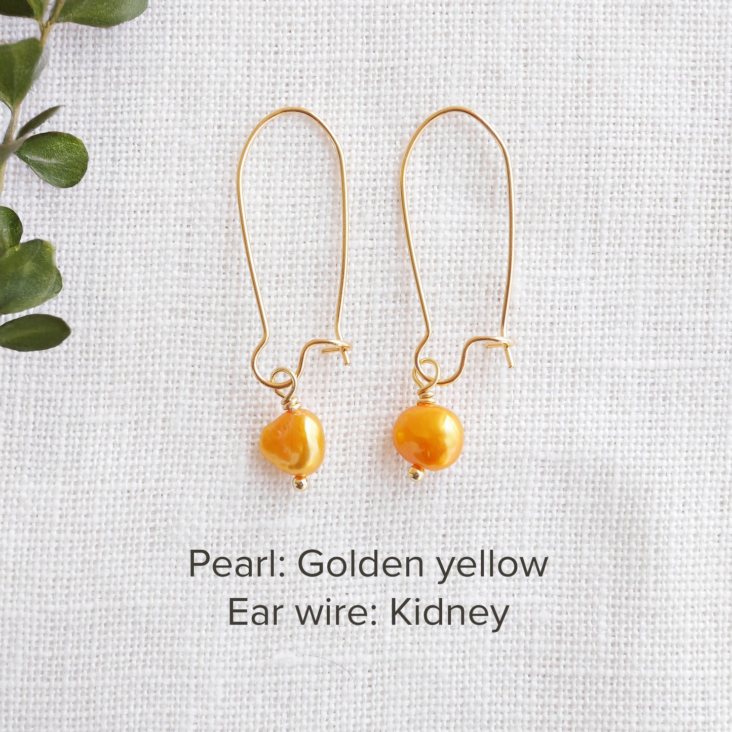 A pair of baroque freshwater pearl earrings on a white cloth.
