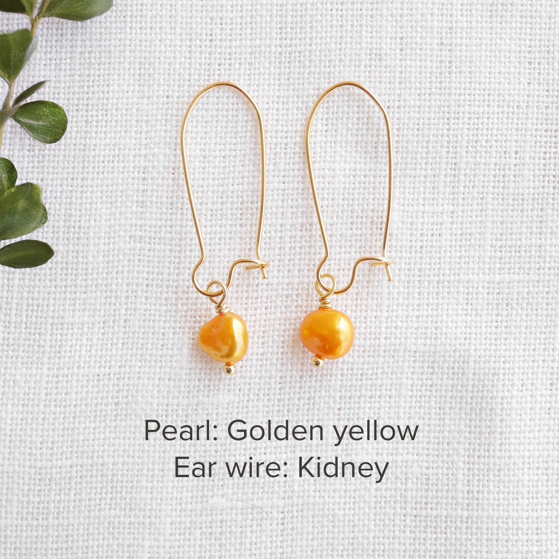 A pair of baroque freshwater pearl earrings on a white cloth.