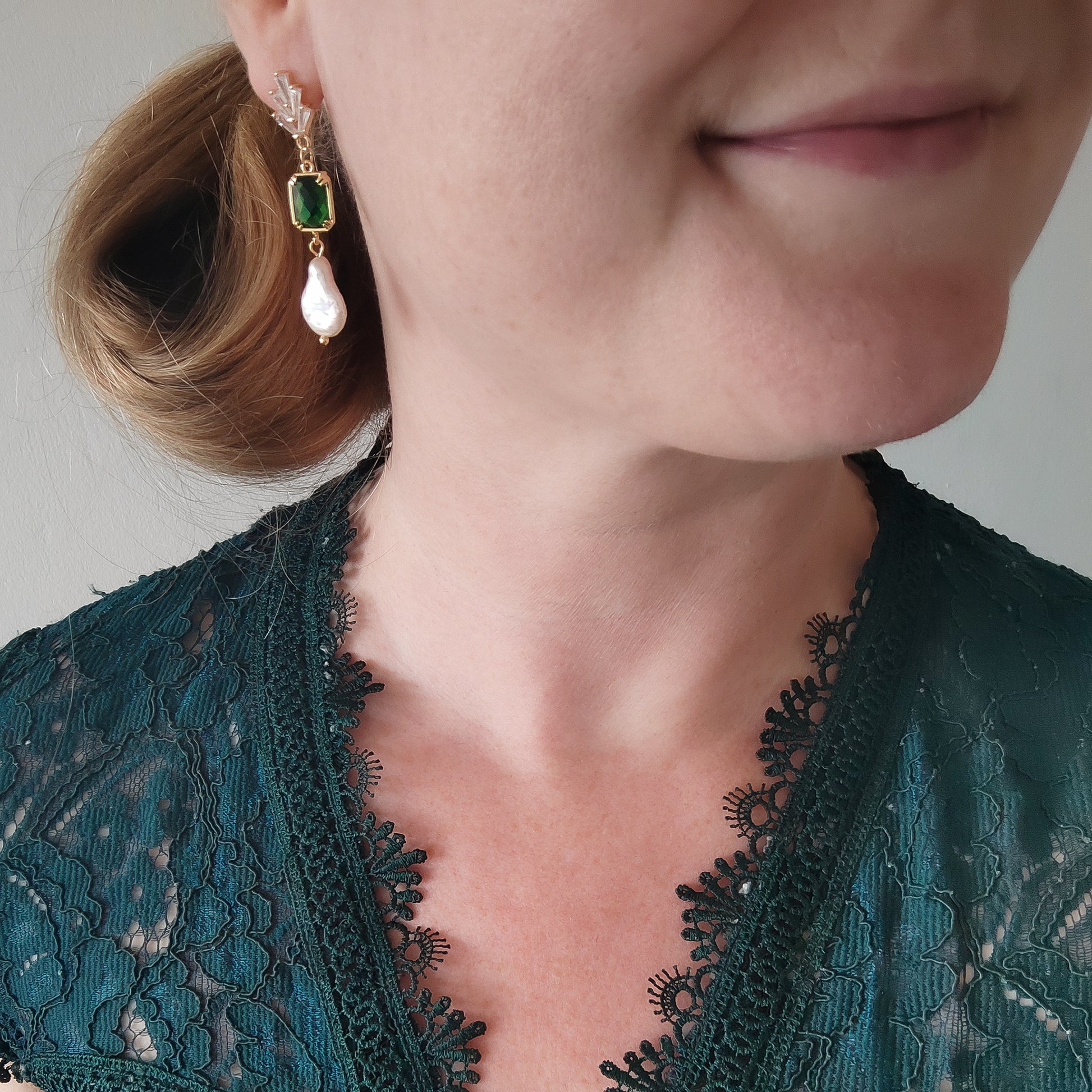 Woman wearing green art deco style dangle earrings.