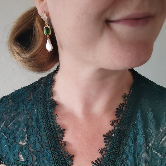 Woman wearing green art deco style dangle earrings.