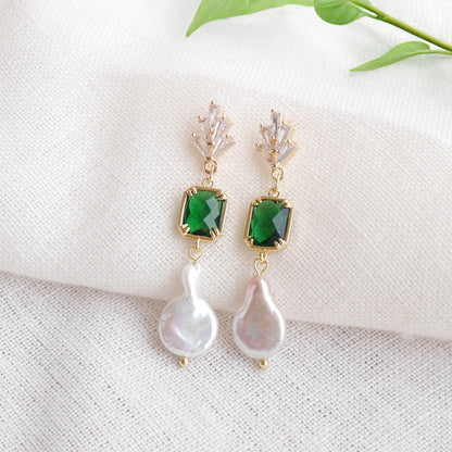 Green art deco style dangle earrings on a white cloth.