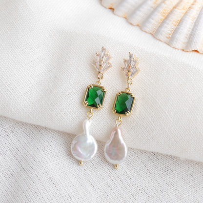 Green art deco style dangle earrings on a white cloth.