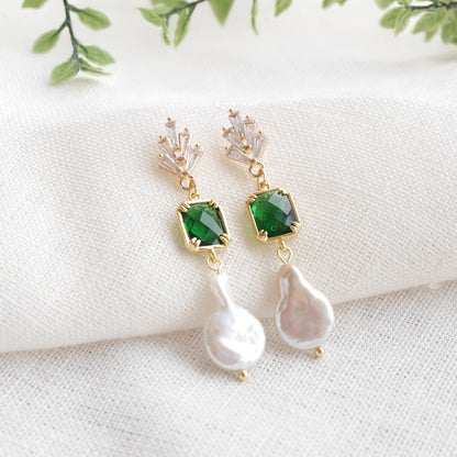 Green art deco style dangle earrings on a white cloth.
