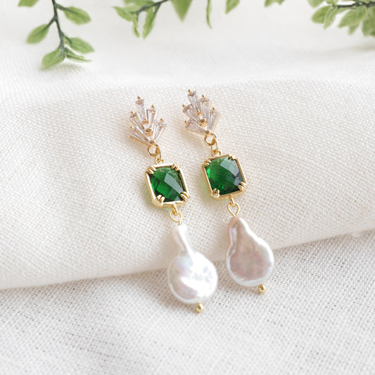 Green art deco style dangle earrings on a white cloth.