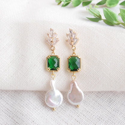 Green art deco style dangle earrings on a white cloth.