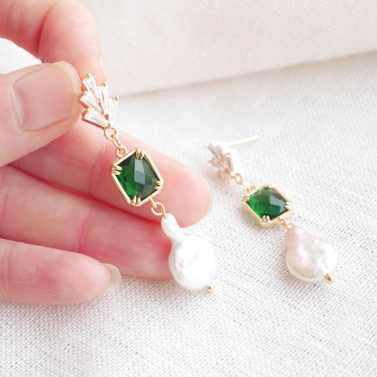 Green art deco style dangle earrings on a white cloth.