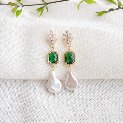 Green art deco style dangle earrings on a white cloth.