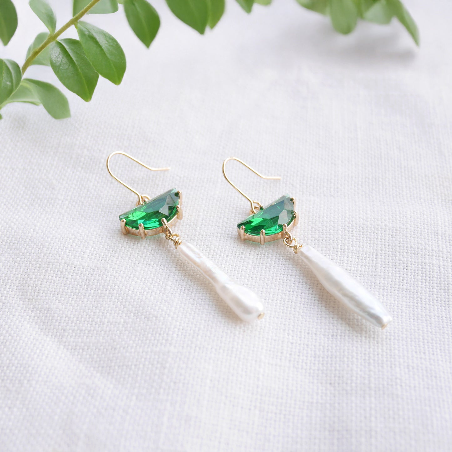 Green biwa pearl earrings on a white cloth.
