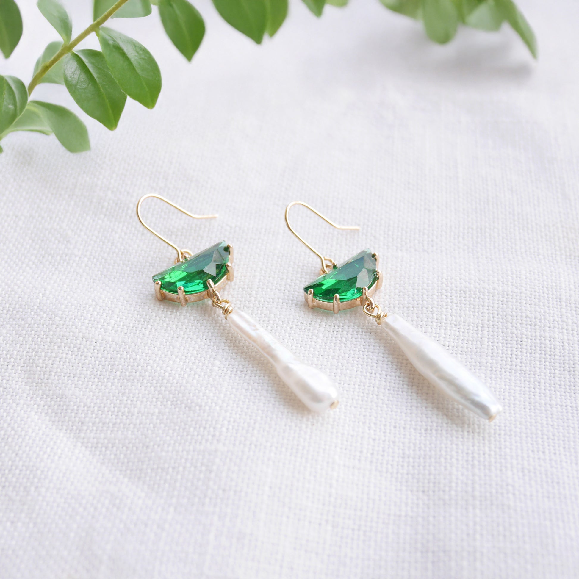 Green biwa pearl earrings on a white cloth.