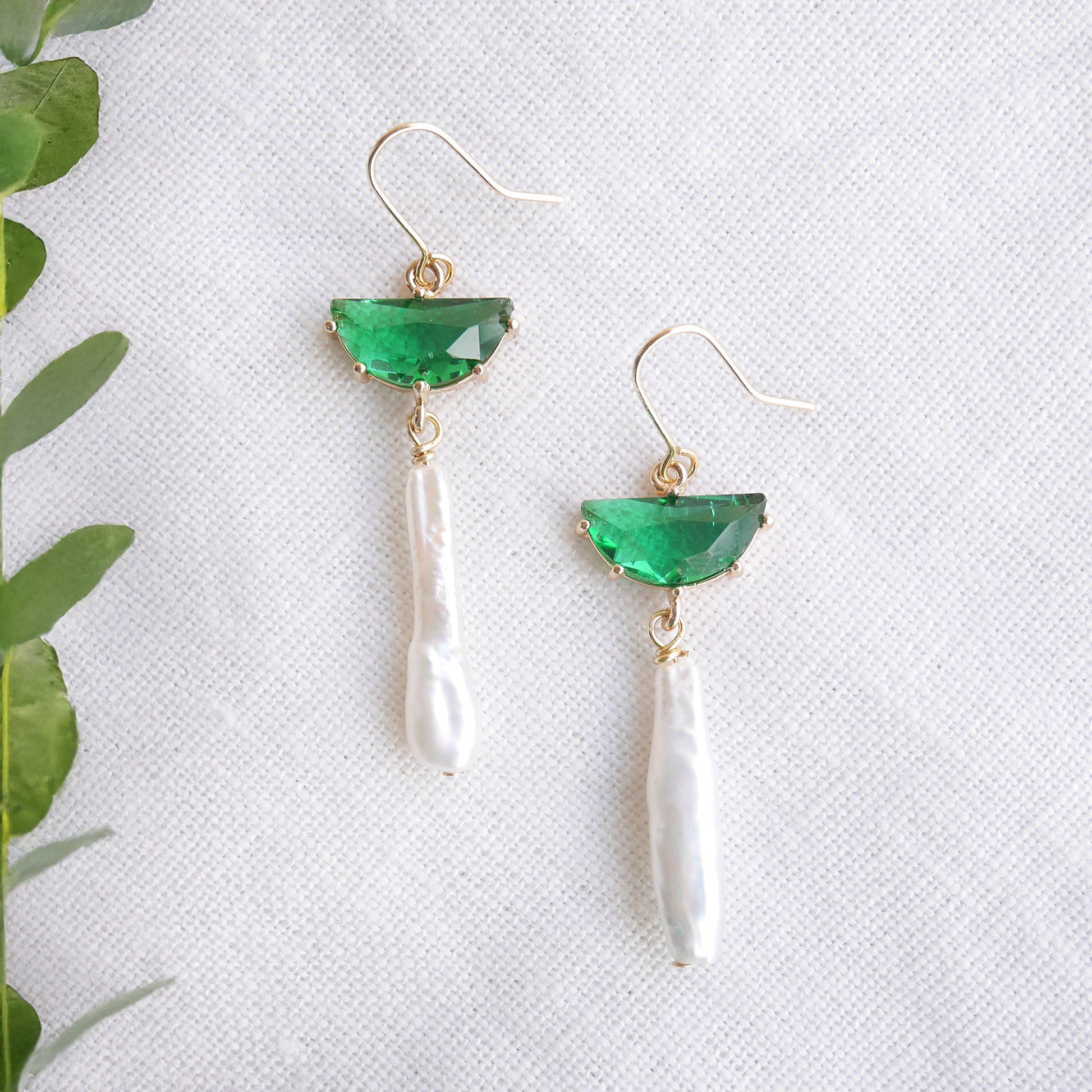 Green biwa pearl earrings on a white cloth.