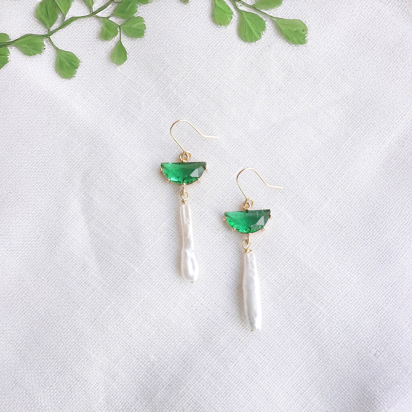 Green biwa pearl earrings on a white cloth.