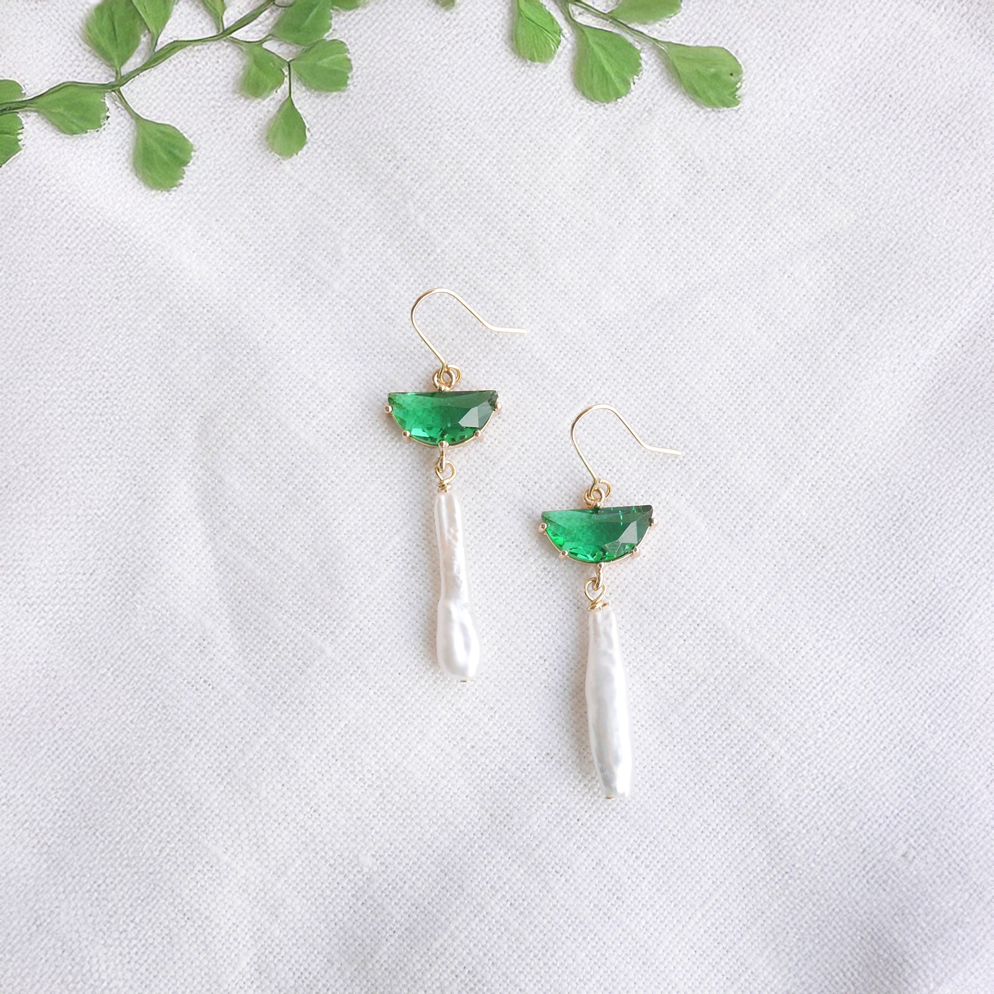 Green biwa pearl earrings on a white cloth.