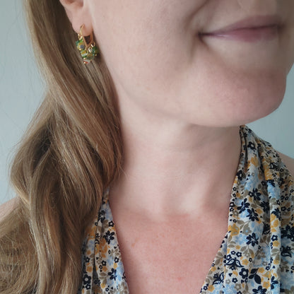 Woman wearing green glass chip hoop earrings.