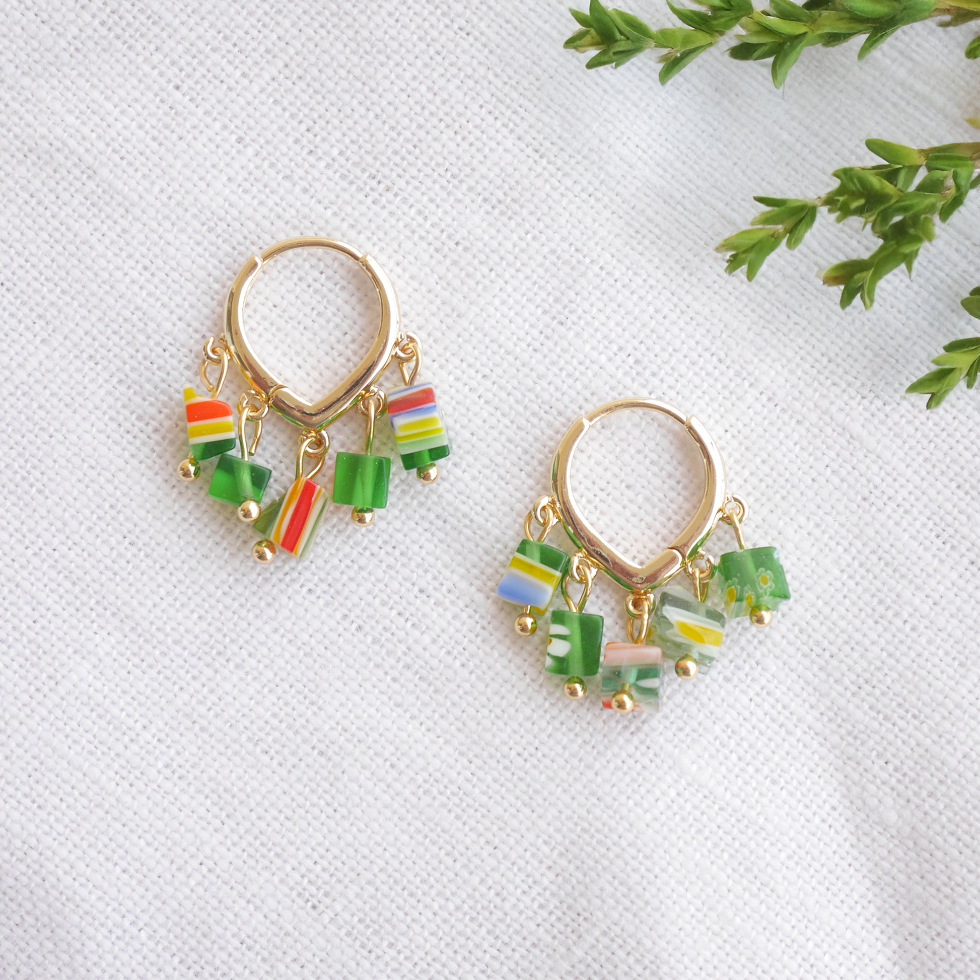 Green glass chip hoop earrings on a white cloth.