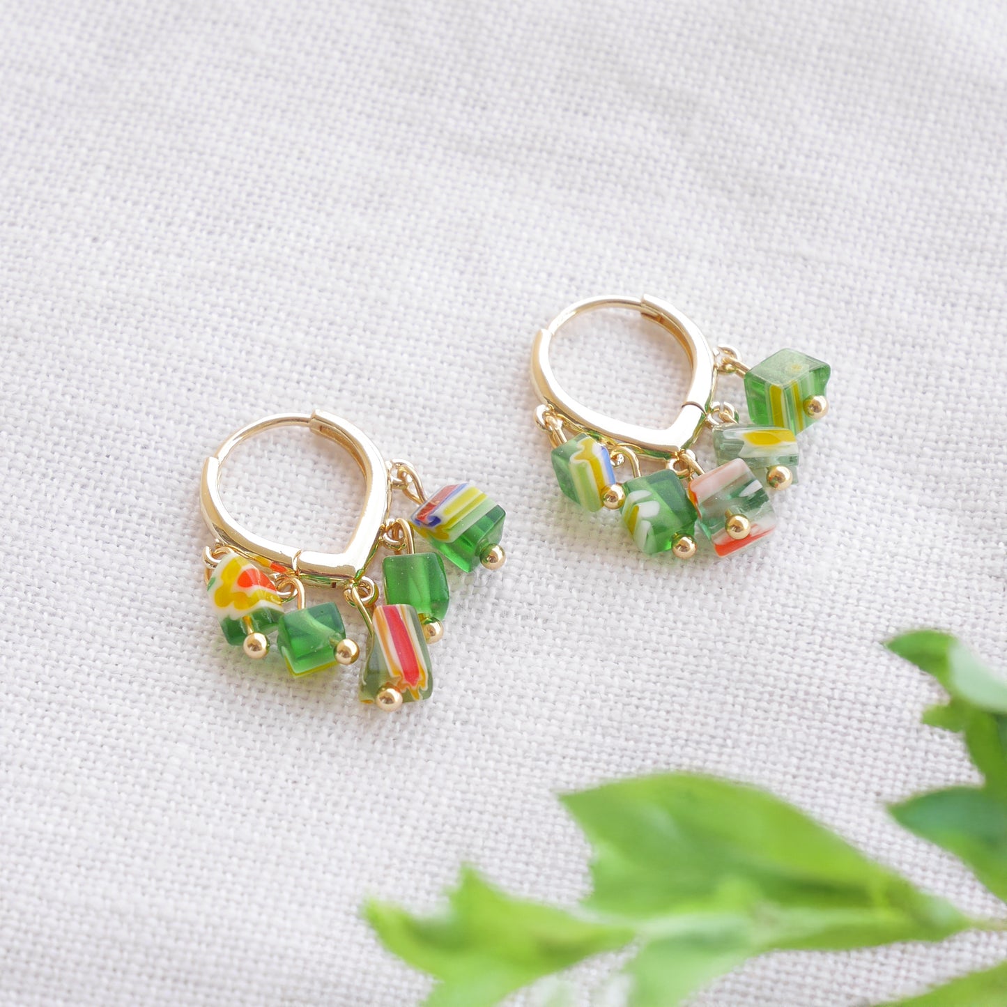 Green glass chip hoop earrings on a white cloth.