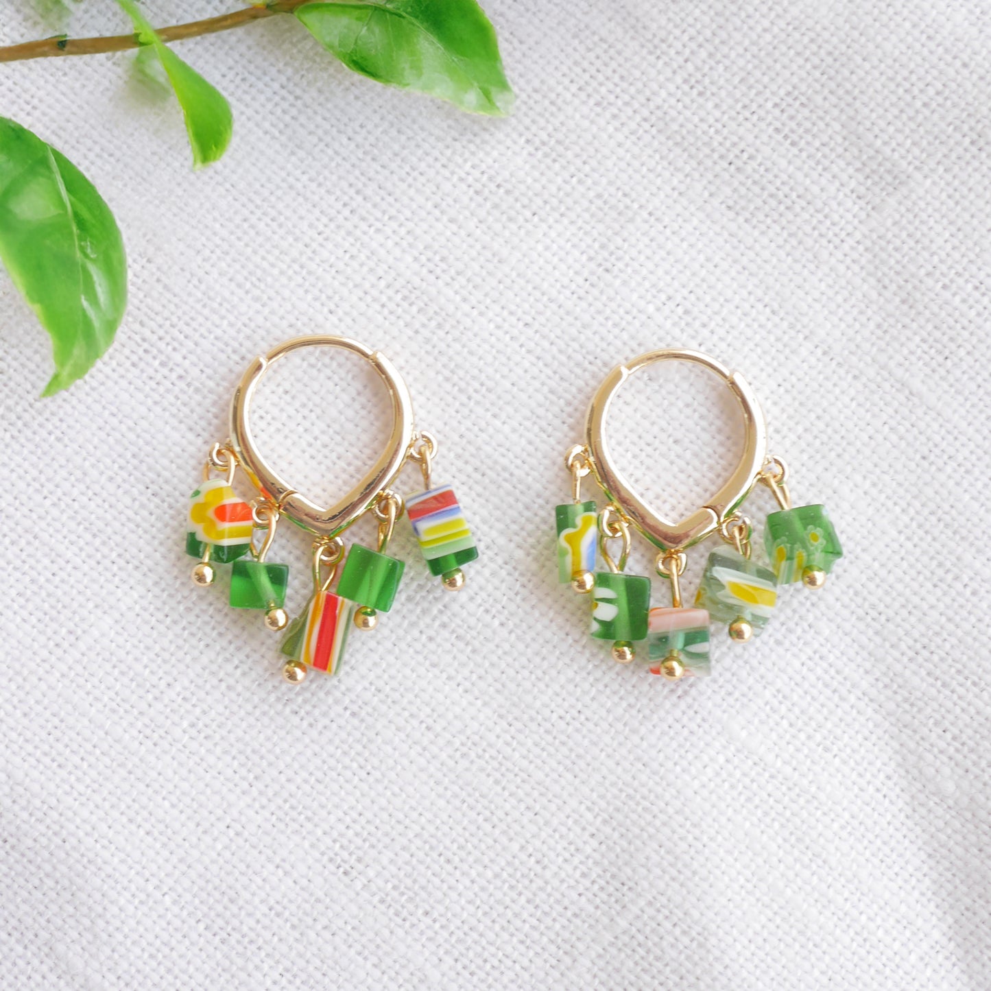 Green glass chip hoop earrings on a white cloth.