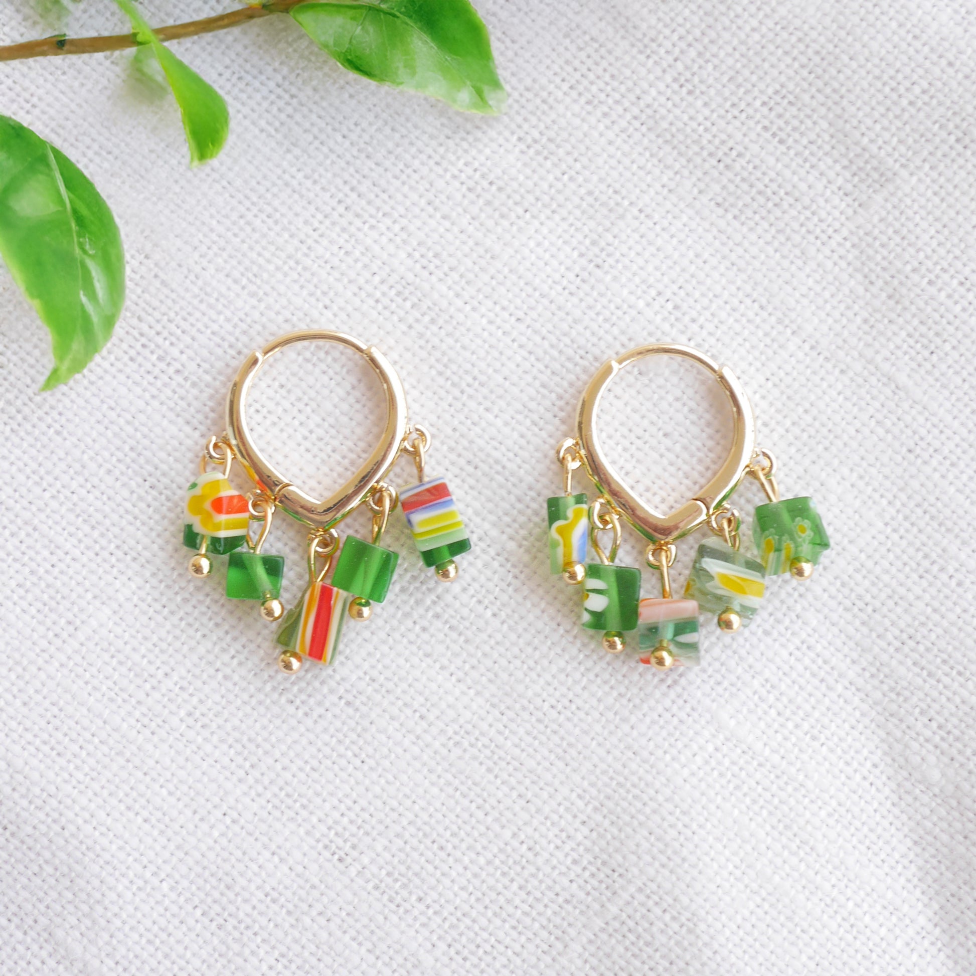 Green glass chip hoop earrings on a white cloth.