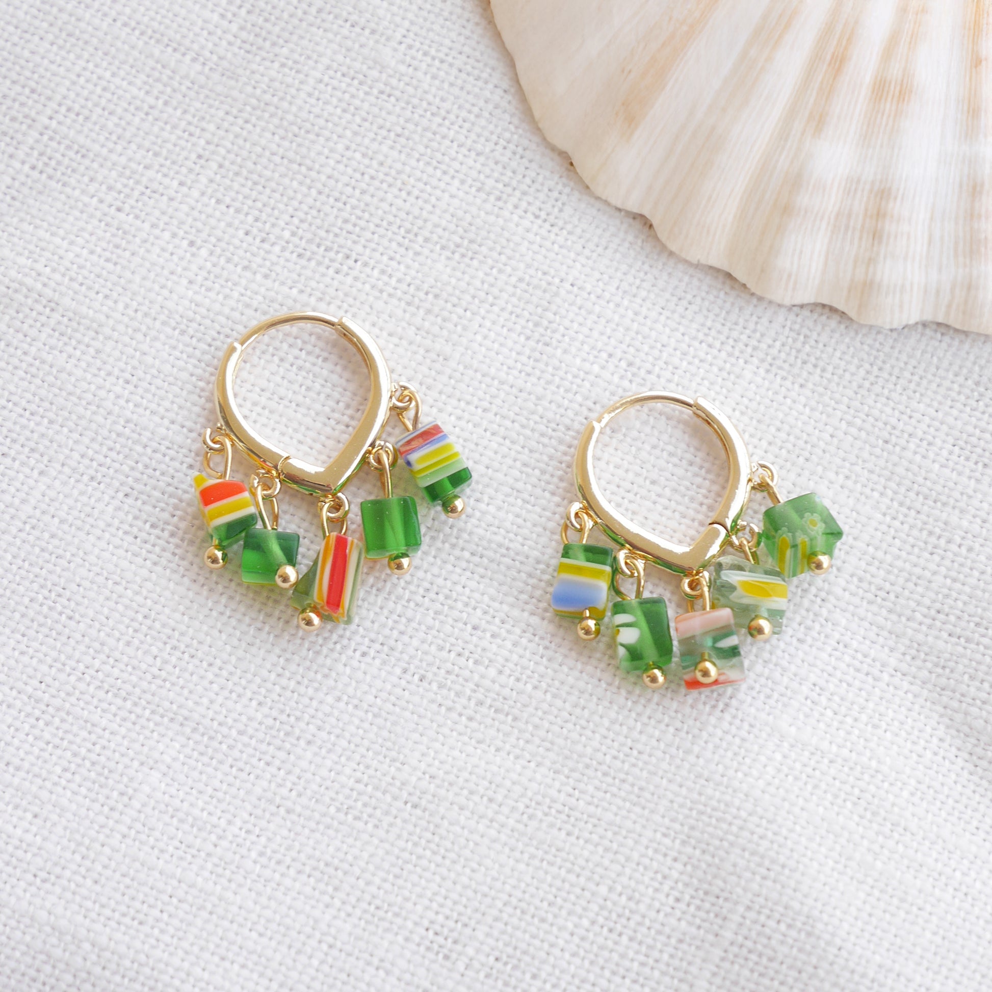 Green glass chip hoop earrings on a white cloth.