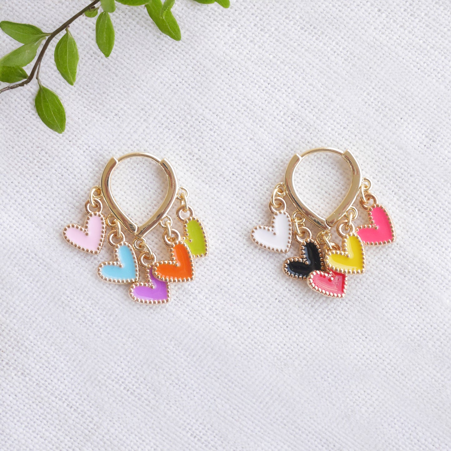 Colorful heart cluster hoop earrings on a white cloth.