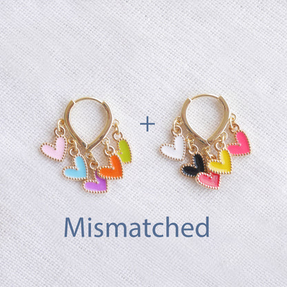 Colorful heart cluster hoop earrings on a white cloth.