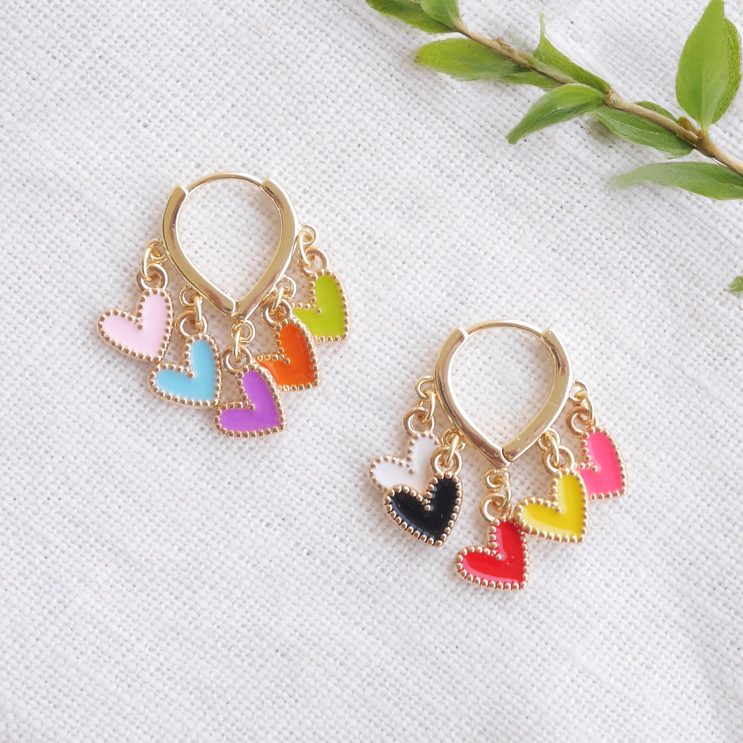 Colorful heart cluster hoop earrings on a white cloth.