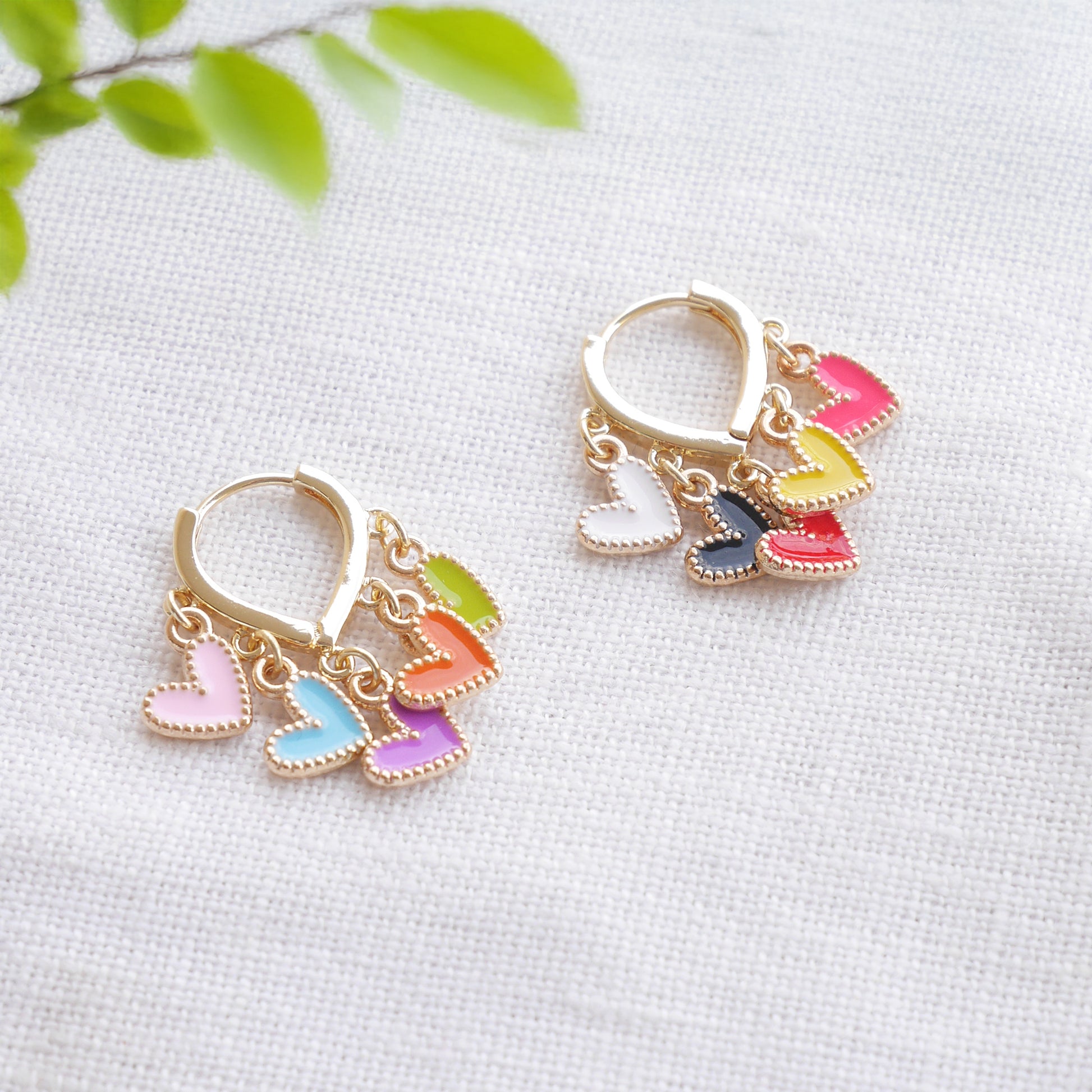 Colorful heart cluster hoop earrings on a white cloth.
