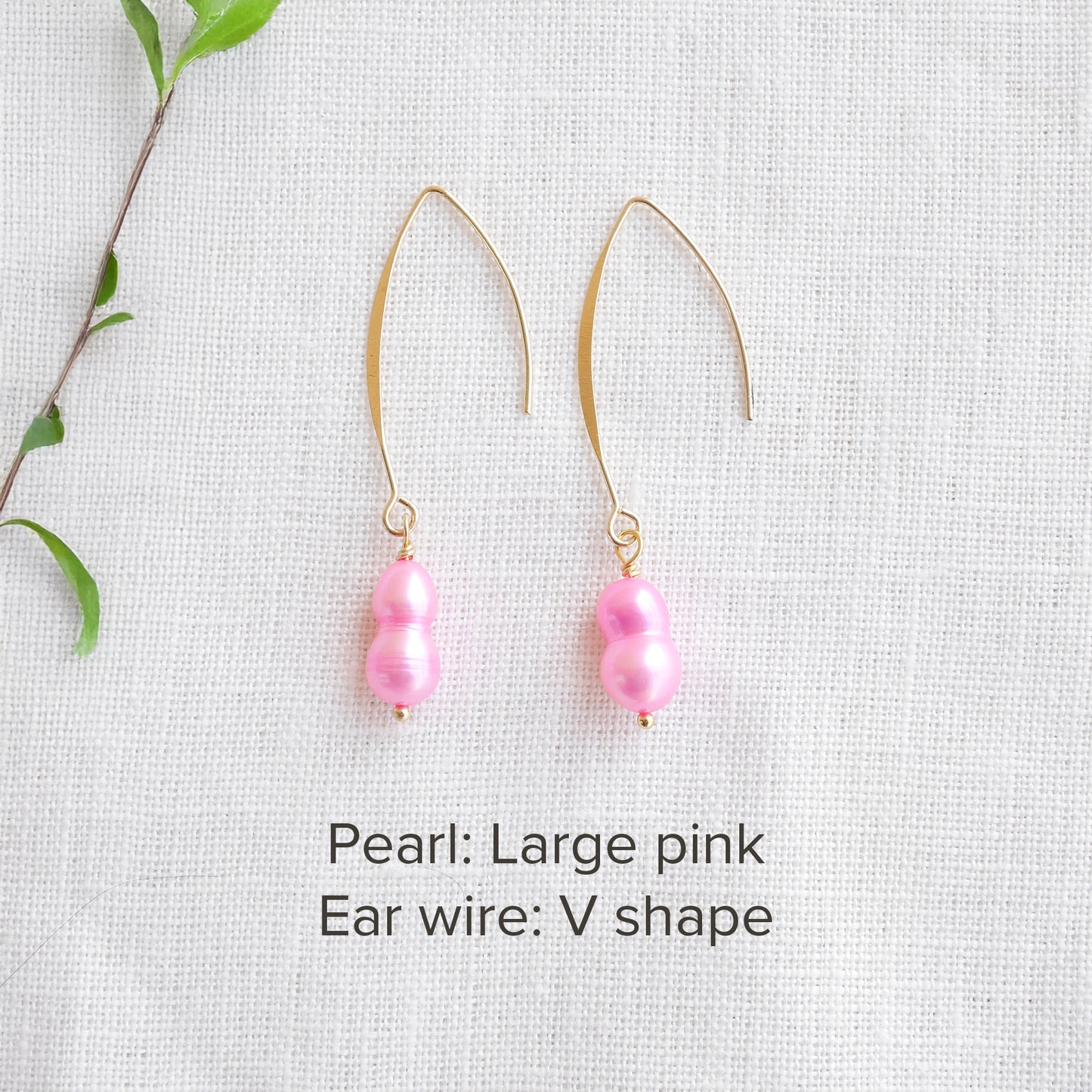 A pair of baroque freshwater pearl earrings on a white cloth.