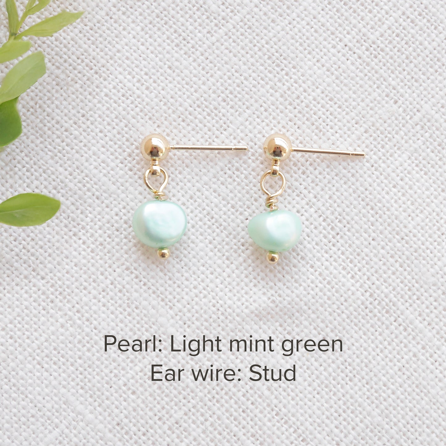 A pair of baroque freshwater pearl earrings on a white cloth.