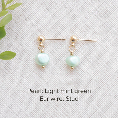 A pair of baroque freshwater pearl earrings on a white cloth.