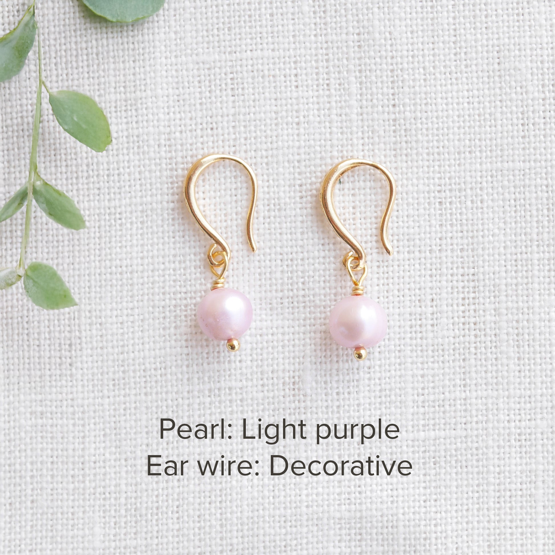 A pair of baroque freshwater pearl earrings on a white cloth.