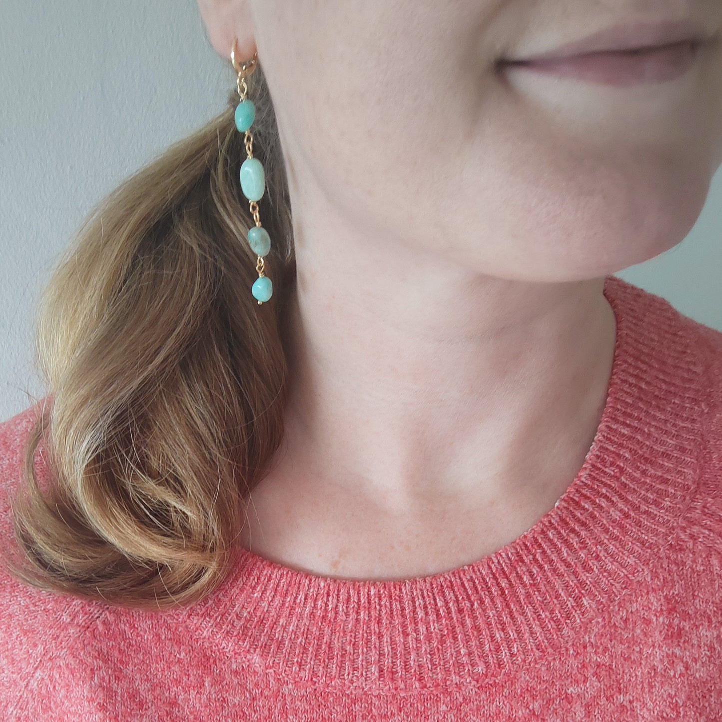 Woman wearing amazonite gemstone long dangle earrings.