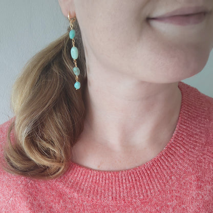 Woman wearing amazonite gemstone long dangle earrings.