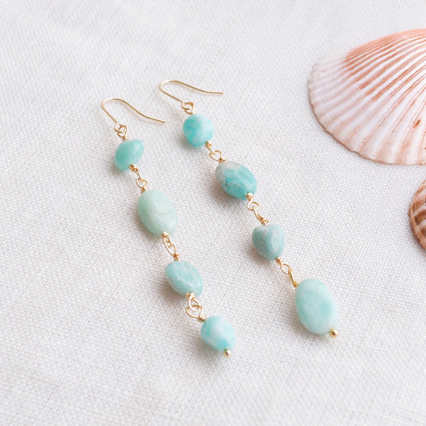 Amazonite gemstone long dangle earrings on a white cloth.