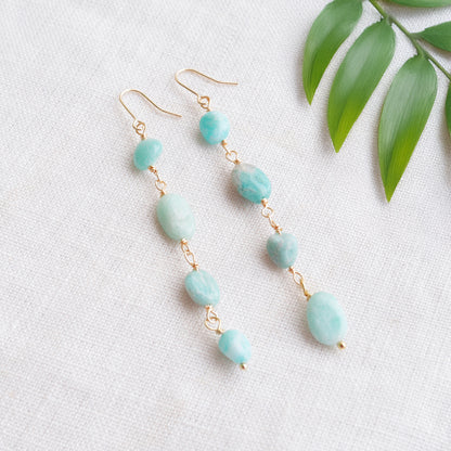 Amazonite gemstone long dangle earrings on a white cloth.