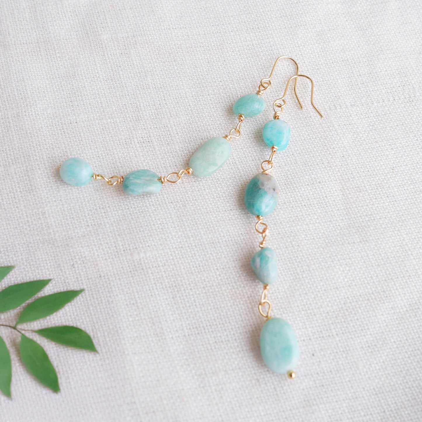 Amazonite gemstone long dangle earrings on a white cloth.