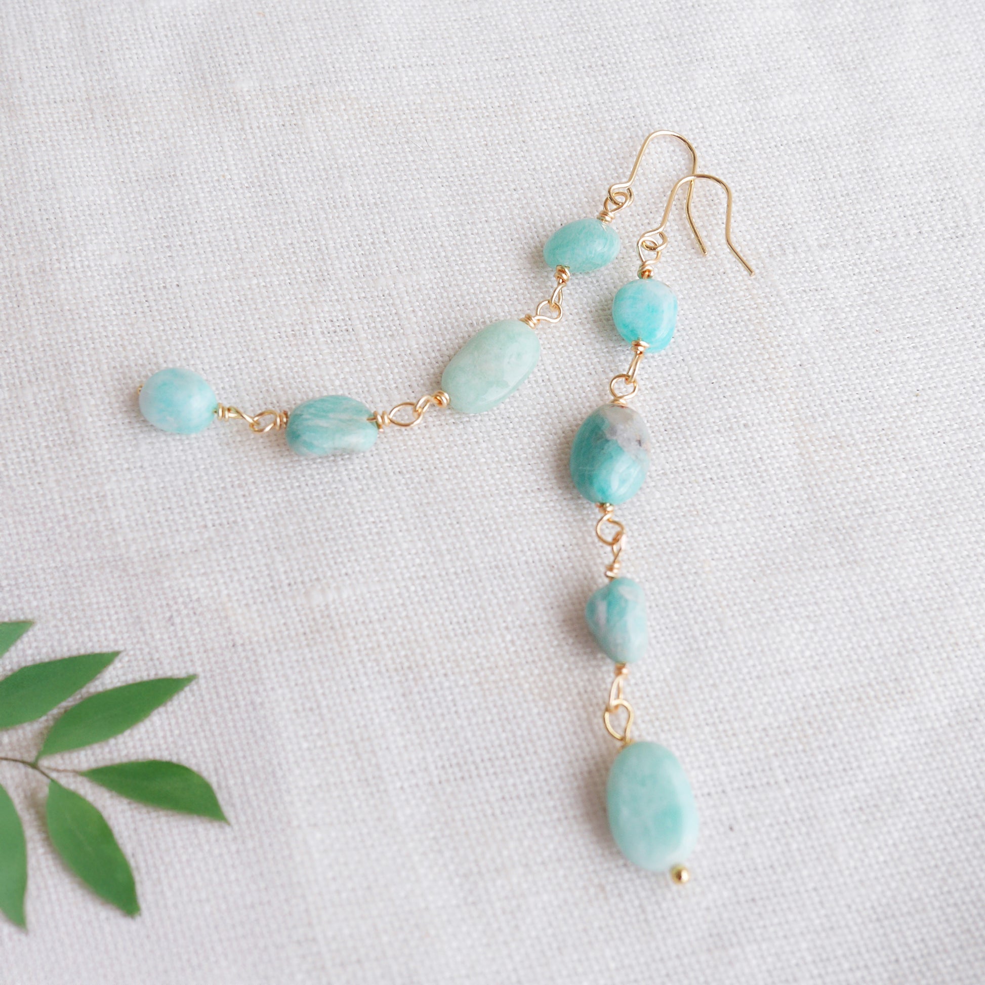 Amazonite gemstone long dangle earrings on a white cloth.