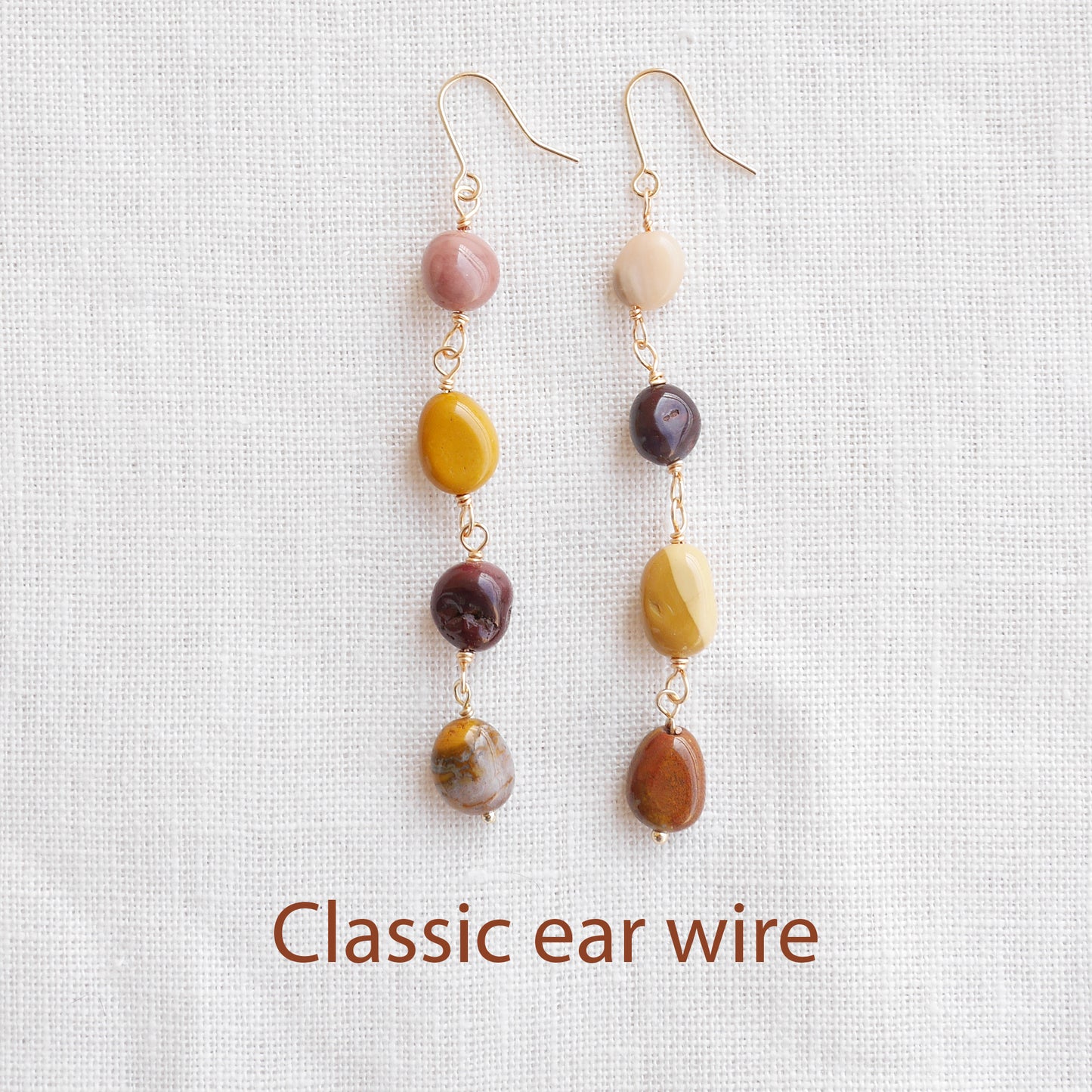 Long jasper stone dangle earrings in earthy mookaite colors, on a white cloth.