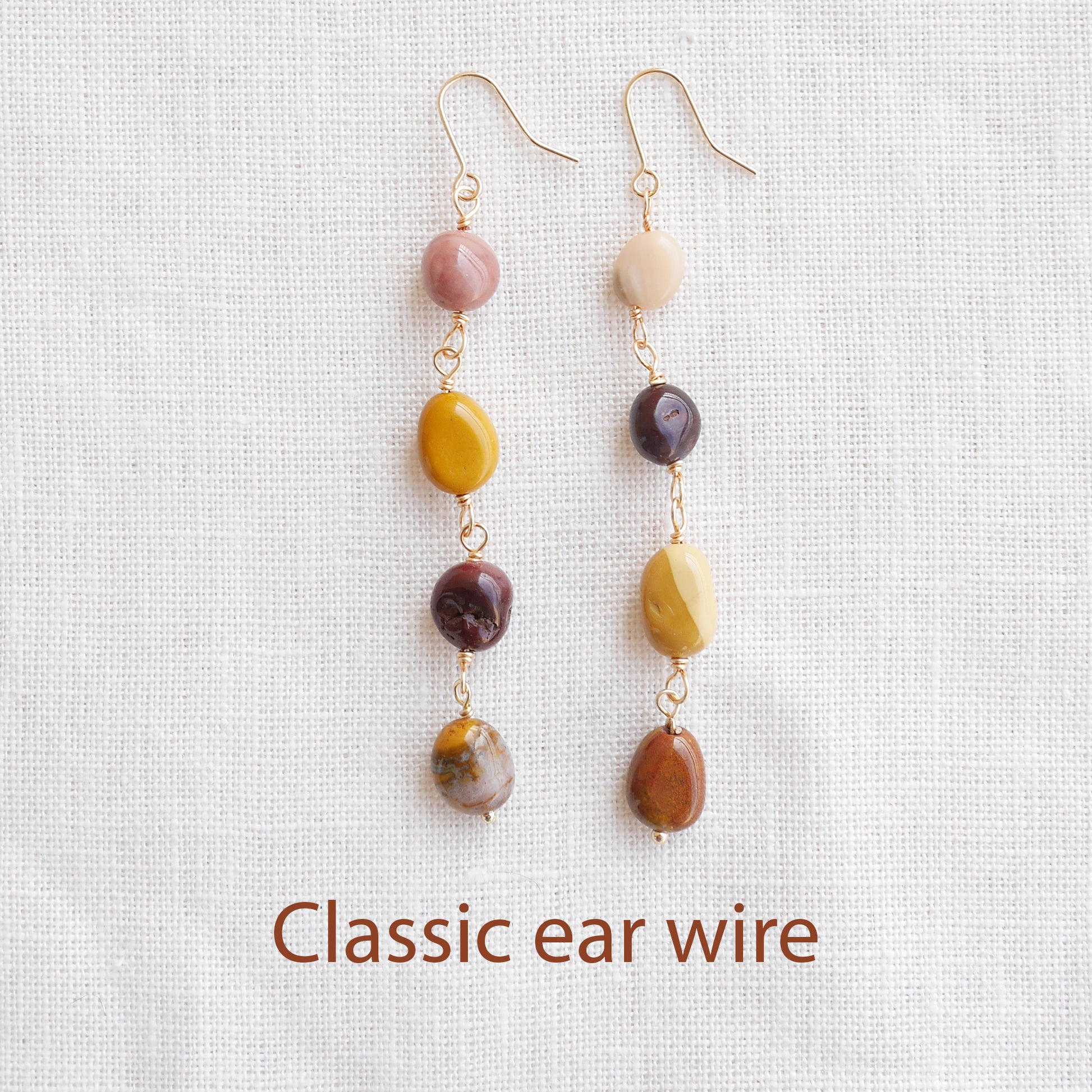 Long jasper stone dangle earrings in earthy mookaite colors, on a white cloth.