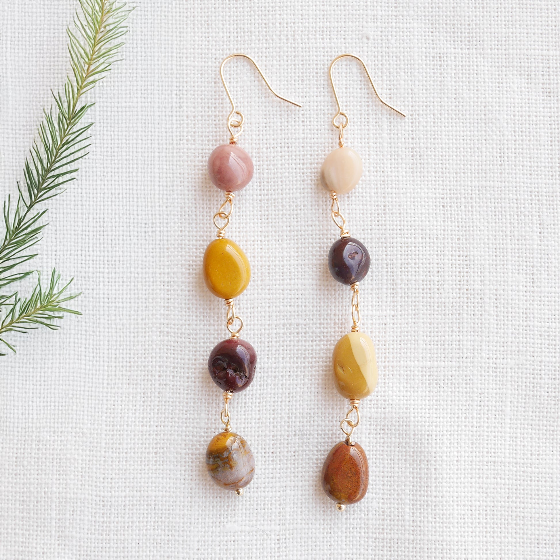 Long jasper stone dangle earrings in earthy mookaite colors, on a white cloth.