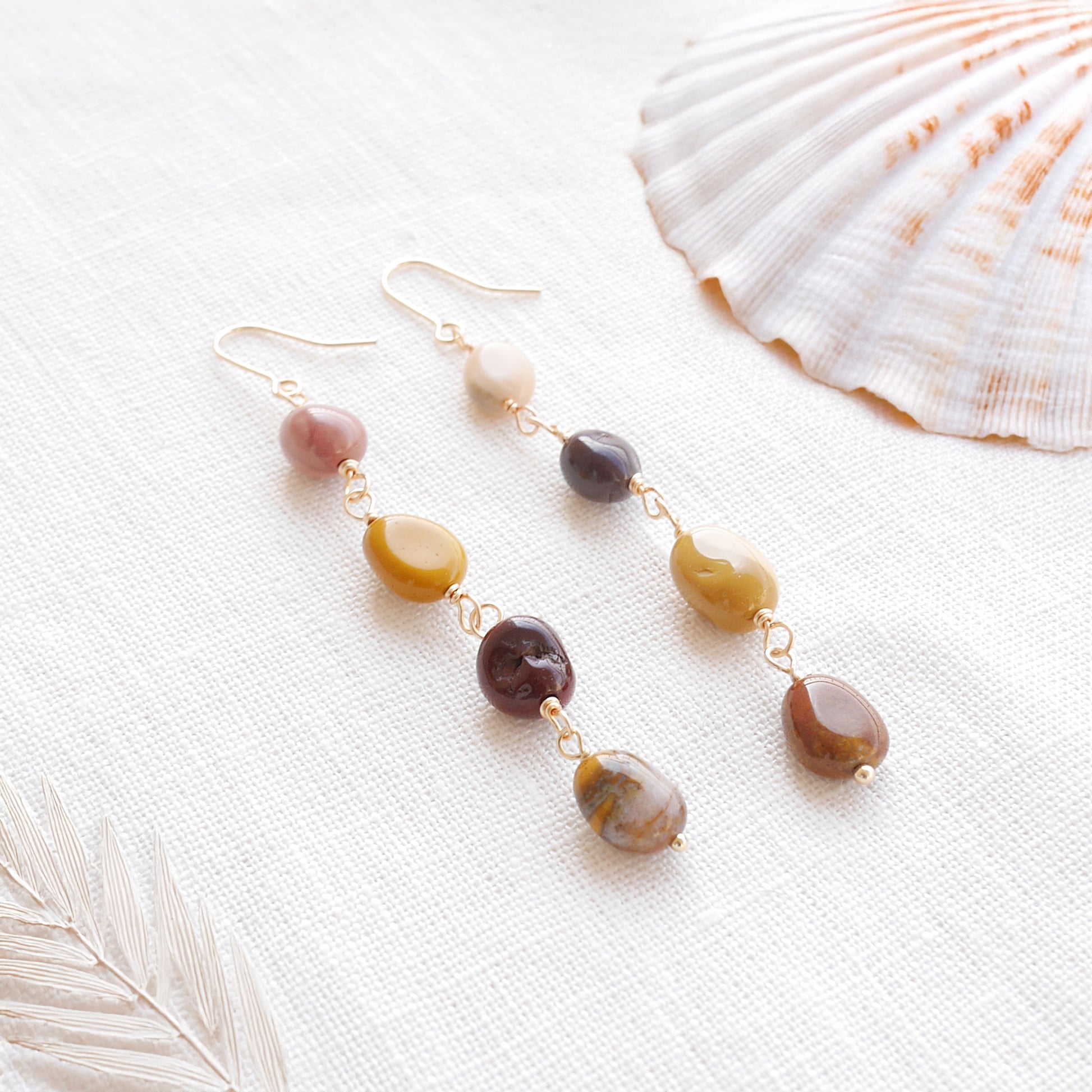 Long jasper stone dangle earrings in earthy mookaite colors, on a white cloth.