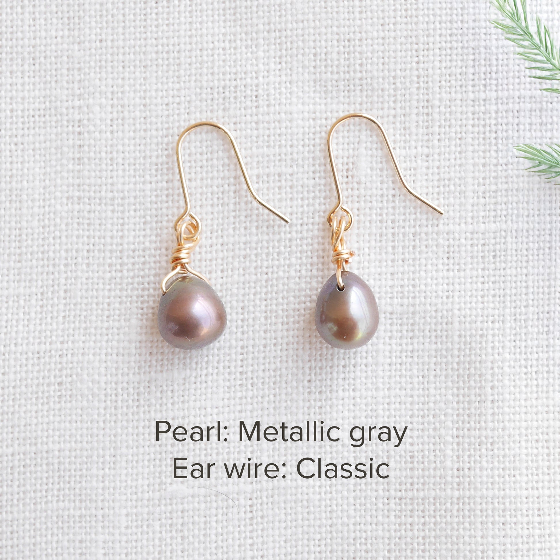 A pair of baroque freshwater pearl earrings on a white cloth.