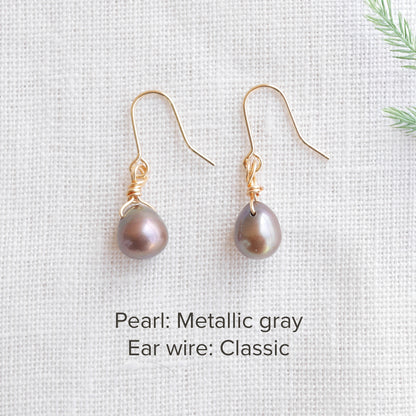 A pair of baroque freshwater pearl earrings on a white cloth.