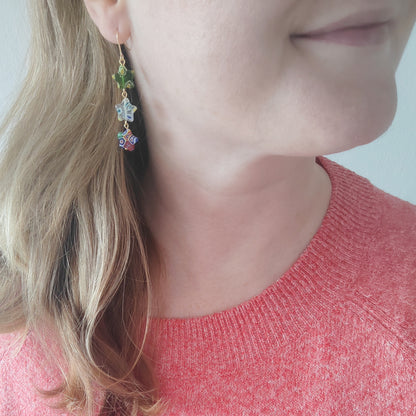 Woman wearing colorful star dangle earrings.