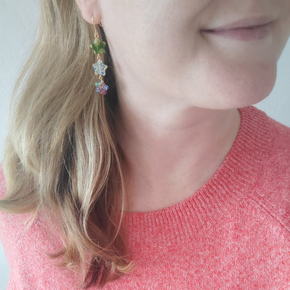 Woman wearing colorful star dangle earrings.
