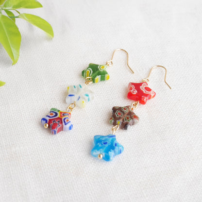 Colorful star dangle earrings with three millefiori star shape glass beads in each earring, on a white cloth.